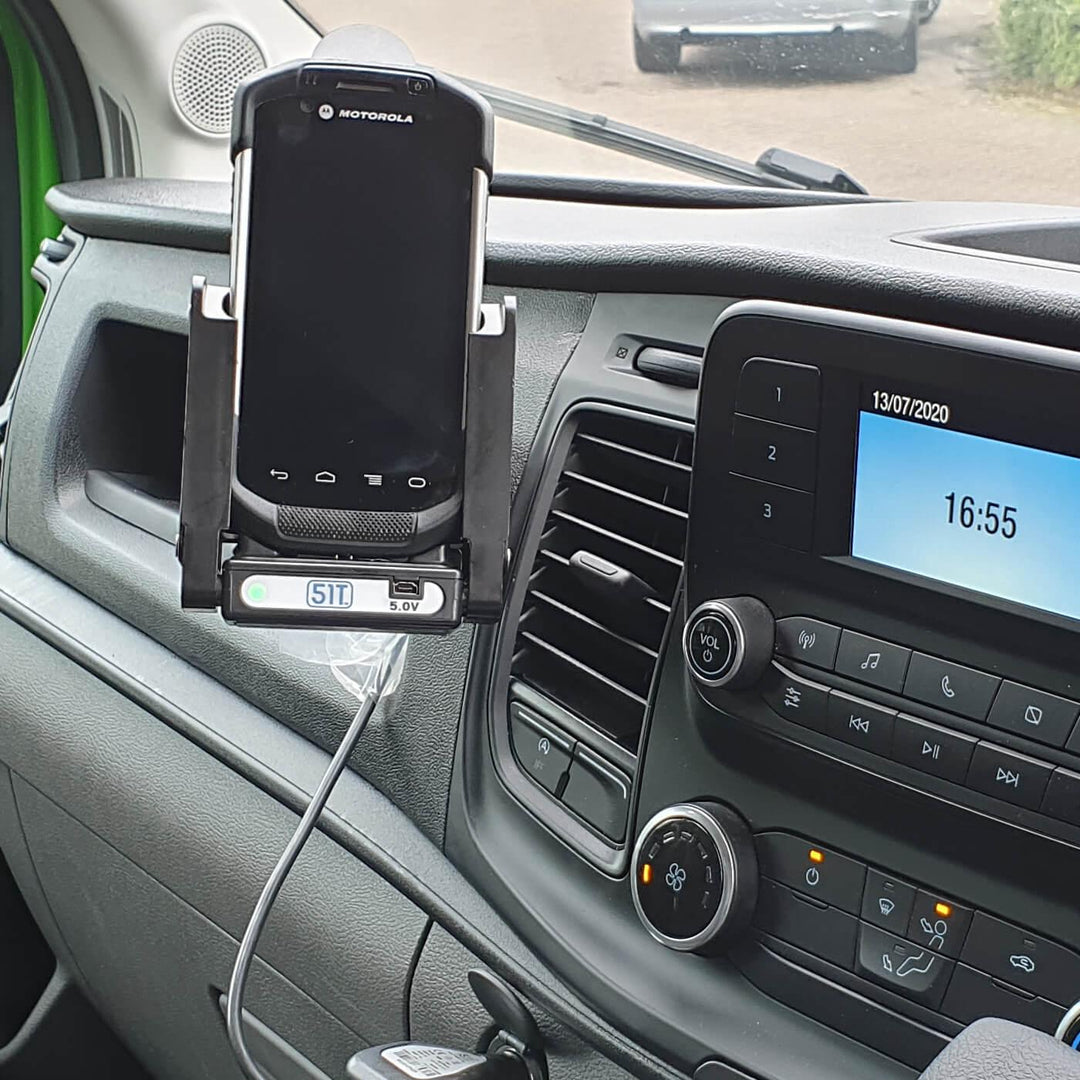 Vehicle dashboard with mounted mobile device in charging cradle and cable connected.