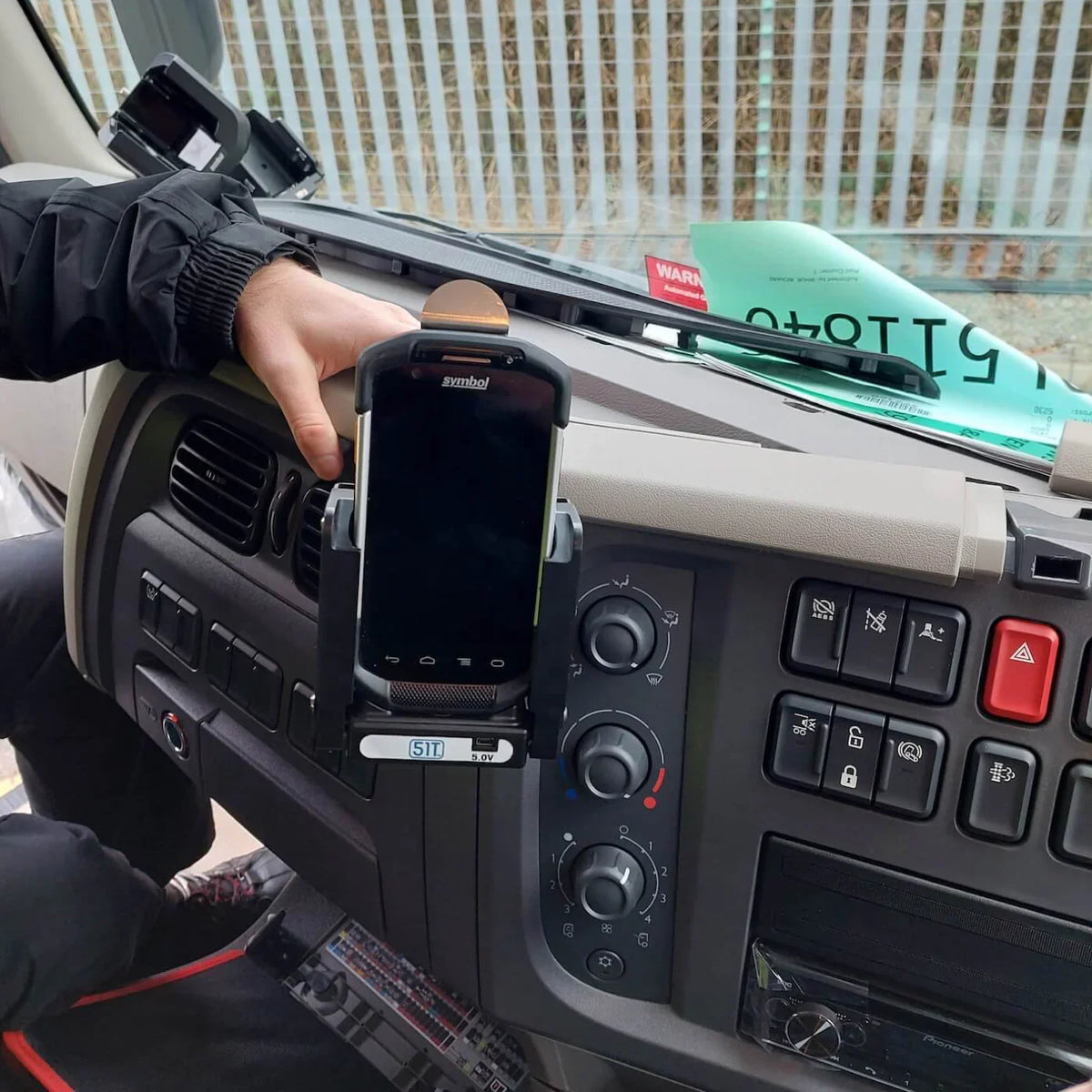Vehicle-mounted barcode scanner cradle installed on truck dashboard for secure charging.